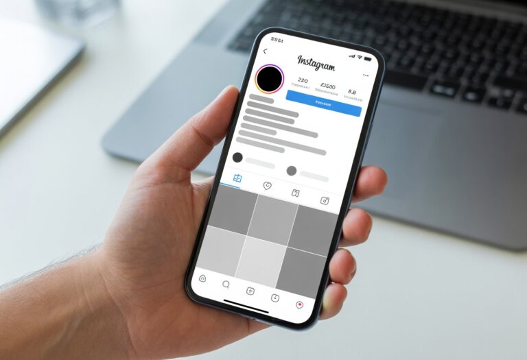 Pessoa segurando um celular mostrando uma página de perfil do Instagram com informações e fotos ocultas, indicando que o perfil está bloqueado.