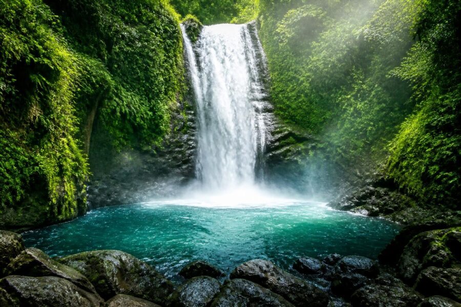 Cachoeira majestosa cercada por floresta tropical densa com água caindo em uma piscina cristalina abaixo.