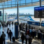 Terminal de aeroporto movimentado em Buenos Aires com passageiros, balcões de check-in e aviões estacionados ao fundo.