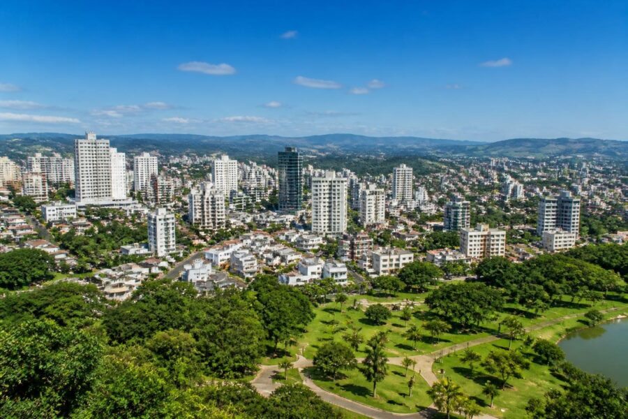 Vista panorâmica de cidades próximas a Belo Horizonte com prédios, áreas verdes e céu azul.