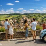 Grupo de turistas aproveitando um passeio de um dia na zona rural próxima a Paris, com casas tradicionais e colinas verdes ao fundo.